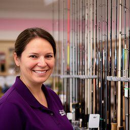 Staff member Marta Silva smiling beside a neatly organised rod rack inside the shop
